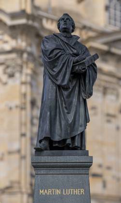 Monument to the reformer Martin Luther 1483 1546 with a Bible in his hand in front of the Church of Our Lady at Neumarkt in Dresden On October 31, Protestant Christians celebrate Reformation Day Martin Luther is said to have slammed his church-critical 95 Theses on the door of the Castle Church in Wittenberg Saxony An