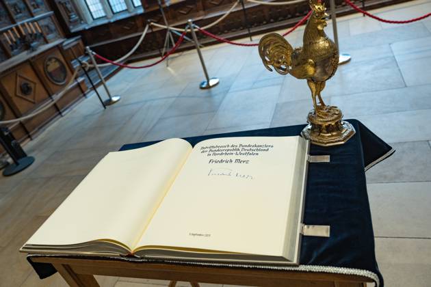 Federal Chancellor Friedrich Merz signs the Golden Book of the City of Münster in the Peace Hall, view of the Golden Book with the Federal Chancellors signature and the traditional Golden Rooster of the City of Münster Inaugural visit of the Federal Chancellor to North Rhine-Westphalia Münster , Münster North Rhine-Westphalia Germany City Hall