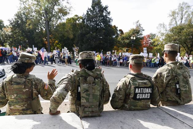 October 18, 2025, Washington Dc, Washington Dc, USA: National Guard members are seen while demonstrators take part in a protest against the Donald Trump administration during the No Kings national rally on October 18, 2025, in Washington, DC, USA. Millions of people across the nation joined the No Kings protest to demonstrate their disapproval of the current US administration. The No Kings Day of Defiance has been organized to reject authoritarianism, billionaire-first politics, and the militarization of the countryÃ¢â‚¬â ¢s democracy, according to a statement by organizers. Washington Dc USA - ZUMAk203 20251018_znp_k203_017 Copyright: xAashishxKiphayetx