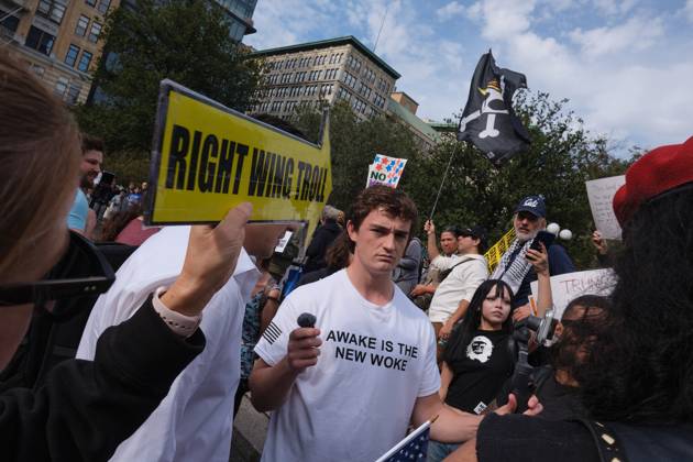 October 19, 2025, New York, New York, USA: A protester holds up a yellow arrow that reads, Ã¢â‚¬oeRight Wing TrollÃ¢â‚¬Â pointed towards right wing social media influencer, Nick Shirley wearing a Turning Point tee shirt with the phrase, Ã¢â‚¬oeAwake Is The New WokeÃ¢â‚¬Â who is attempting to engage people who attended the New York City No Kings protest with MAGA talking points to solicit reactions for a livestream video in Union Square. New York USA - ZUMAl171 20251019_znp_l171_002 Copyright: xEdnaxLeshowitzx