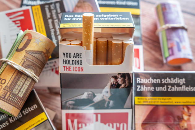 Bavaria, Germany - July 2, 2026: Several cigarette packs next to a euro bill symbolize the financial impact of smoking. The image represents tobacco taxes, potential tax increases, rising cigarette prices, and higher costs for consumers.