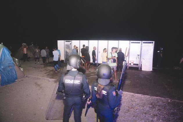 October 3, 2026, Ceuta, Ceuta, Spain: Riot police officers stand in front of the portable toilets of a makeshift migrant camp in Ceuta at night. Riot police escorted firefighters through the camp on the night of October 3 to put out the fires that people living there use to cook their food. Thousands of migrants, most of them young Moroccan men, have been living in makeshift settlements in the Spanish North African enclave of Ceuta since a mass arrival at the end of July 2026 set off a migration and political crisis. Ceuta Spain - ZUMAs392 20261003_zip_s392_005 Copyright: xFabianxSuspensivox