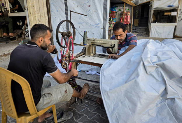 Palestinian Tailor Repairs Tent Covers for Displaced Families in Khan Younis Palestinian tailor Shaaban al-Tabash repairs and assembles tarpaulins and plastic sheets using rudimentary methods to reinforce the tents of displaced Palestinians and protect them from cold weather and rain in Khan Younis, in the southern Gaza Strip, on October 4, 2026. As winter approaches, shortages of protective supplies and the deterioration of many tents after nearly three years of war are worsening living conditions, while al-Tabash uses available materials to extend the life of shelters that have become the last refuge for thousands of displaced people. Photo by Tariq Mohammad APA Images Khan Yunis Gaza Strip Palestinian Territory 041026_Khan_Yunis_TM_01( Copyright: xapaimagesxTariqxMohammad xapaimagesx