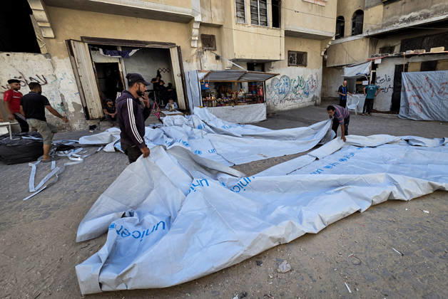 Palestinian Tailor Repairs Tent Covers for Displaced Families in Khan Younis Palestinian tailor Shaaban al-Tabash repairs and assembles tarpaulins and plastic sheets using rudimentary methods to reinforce the tents of displaced Palestinians and protect them from cold weather and rain in Khan Younis, in the southern Gaza Strip, on October 4, 2026. As winter approaches, shortages of protective supplies and the deterioration of many tents after nearly three years of war are worsening living conditions, while al-Tabash uses available materials to extend the life of shelters that have become the last refuge for thousands of displaced people. Photo by Tariq Mohammad APA Images Khan Yunis Gaza Strip Palestinian Territory 041026_Khan_Yunis_TM_01( Copyright: xapaimagesxTariqxMohammad xapaimagesx