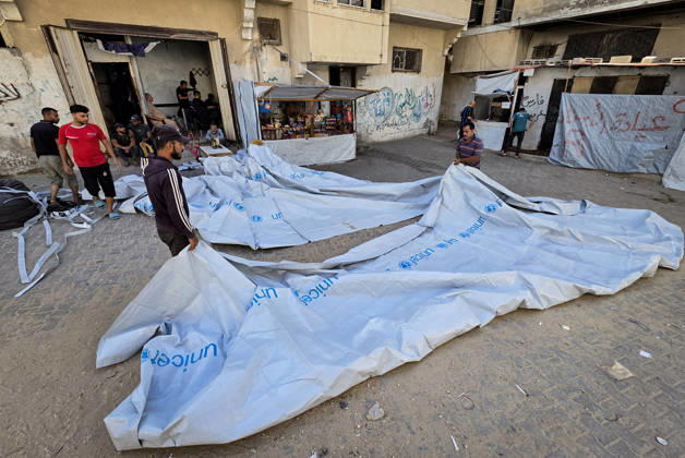 Palestinian Tailor Repairs Tent Covers for Displaced Families in Khan Younis Palestinian tailor Shaaban al-Tabash repairs and assembles tarpaulins and plastic sheets using rudimentary methods to reinforce the tents of displaced Palestinians and protect them from cold weather and rain in Khan Younis, in the southern Gaza Strip, on October 4, 2026. As winter approaches, shortages of protective supplies and the deterioration of many tents after nearly three years of war are worsening living conditions, while al-Tabash uses available materials to extend the life of shelters that have become the last refuge for thousands of displaced people. Photo by Tariq Mohammad APA Images Khan Yunis Gaza Strip Palestinian Territory 041026_Khan_Yunis_TM_01( Copyright: xapaimagesxTariqxMohammad xapaimagesx
