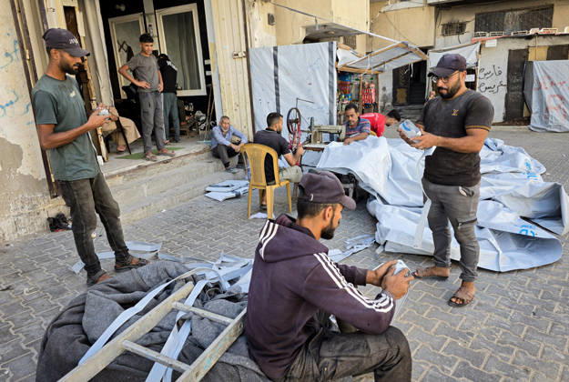 Palestinian Tailor Repairs Tent Covers for Displaced Families in Khan Younis Palestinian tailor Shaaban al-Tabash repairs and assembles tarpaulins and plastic sheets using rudimentary methods to reinforce the tents of displaced Palestinians and protect them from cold weather and rain in Khan Younis, in the southern Gaza Strip, on October 4, 2026. As winter approaches, shortages of protective supplies and the deterioration of many tents after nearly three years of war are worsening living conditions, while al-Tabash uses available materials to extend the life of shelters that have become the last refuge for thousands of displaced people. Photo by Tariq Mohammad APA Images Khan Yunis Gaza Strip Palestinian Territory 041026_Khan_Yunis_TM_01( Copyright: xapaimagesxTariqxMohammad xapaimagesx