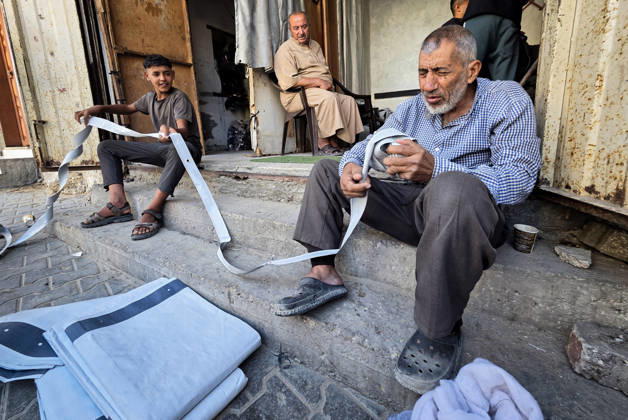 Palestinian Tailor Repairs Tent Covers for Displaced Families in Khan Younis Palestinian tailor Shaaban al-Tabash repairs and assembles tarpaulins and plastic sheets using rudimentary methods to reinforce the tents of displaced Palestinians and protect them from cold weather and rain in Khan Younis, in the southern Gaza Strip, on October 4, 2026. As winter approaches, shortages of protective supplies and the deterioration of many tents after nearly three years of war are worsening living conditions, while al-Tabash uses available materials to extend the life of shelters that have become the last refuge for thousands of displaced people. Photo by Tariq Mohammad APA Images Khan Yunis Gaza Strip Palestinian Territory 041026_Khan_Yunis_TM_01( Copyright: xapaimagesxTariqxMohammad xapaimagesx