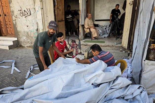 Palestinian Tailor Repairs Tent Covers for Displaced Families in Khan Younis Palestinian tailor Shaaban al-Tabash repairs and assembles tarpaulins and plastic sheets using rudimentary methods to reinforce the tents of displaced Palestinians and protect them from cold weather and rain in Khan Younis, in the southern Gaza Strip, on October 4, 2026. As winter approaches, shortages of protective supplies and the deterioration of many tents after nearly three years of war are worsening living conditions, while al-Tabash uses available materials to extend the life of shelters that have become the last refuge for thousands of displaced people. Photo by Tariq Mohammad APA Images Khan Yunis Gaza Strip Palestinian Territory 041026_Khan_Yunis_TM_01( Copyright: xapaimagesxTariqxMohammad xapaimagesx