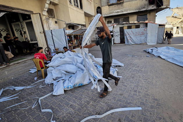 Palestinian Tailor Repairs Tent Covers for Displaced Families in Khan Younis Palestinian tailor Shaaban al-Tabash repairs and assembles tarpaulins and plastic sheets using rudimentary methods to reinforce the tents of displaced Palestinians and protect them from cold weather and rain in Khan Younis, in the southern Gaza Strip, on October 4, 2026. As winter approaches, shortages of protective supplies and the deterioration of many tents after nearly three years of war are worsening living conditions, while al-Tabash uses available materials to extend the life of shelters that have become the last refuge for thousands of displaced people. Photo by Tariq Mohammad APA Images Khan Yunis Gaza Strip Palestinian Territory 041026_Khan_Yunis_TM_01( Copyright: xapaimagesxTariqxMohammad xapaimagesx