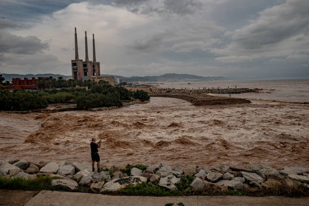 October 4, 2026, Sant Adria Del Besos, Barcelona, Spain: A man takes pictures at the mouth of the Besos River, north of Barcelona, swollen and laden with sediment after a night of torrential rain across Catalonia. The storm brought exceptional rainfall to the Barcelona metropolitan area, with more than 200 litres per square metre recorded in parts of the region. The Besos rose sharply overnight, prompting authorities to warn of an imminent risk of flooding. Sant Adria Del Besos Spain - ZUMAb137 20261004_fap_b137_004 Copyright: xJordixBoixareux