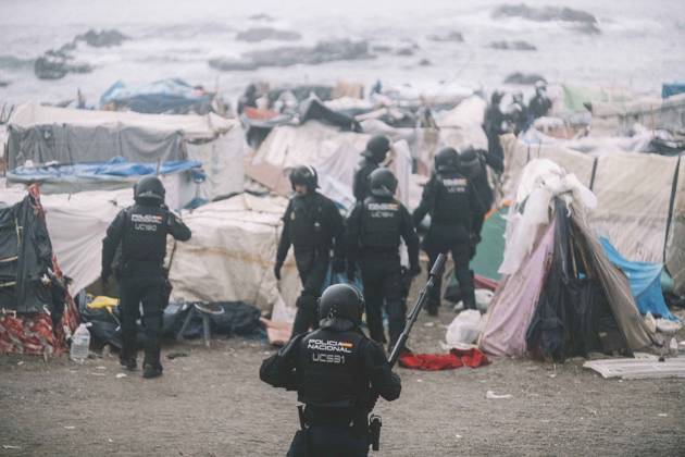 October 4, 2026, Ceuta, Ceuta, Spain: Riot police officers move into the shelters of the makeshift migrant camp on El Trampolin beach in Ceuta, with the sea behind. Spanish National Police began evicting the makeshift camp on El Trampolin beach in Ceuta on October 4, where more than 3,000 migrants, most of them young Moroccan men, were living. Dozens of police vans, armoured vehicles of the Police Intervention Units (UIP), drones and boats took part in the operation. People were taken by bus to the temporary centre at the Tarajal border to be identified, and the authorities plan to clear the beach in phases before October 15. The camp grew after a mass arrival at the end of July 2026 set off a migration and political crisis. Ceuta Spain - ZUMAs392 20261004_zip_s392_017 Copyright: xFabianxSuspensivox