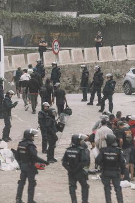 October 4, 2026, Ceuta, Ceuta, Spain: Riot police officers stand among migrants and their bags during the eviction of the makeshift camp on El Trampolin beach in Ceuta. Spanish National Police began evicting the makeshift camp on El Trampolin beach in Ceuta on October 4, where more than 3,000 migrants, most of them young Moroccan men, were living. Dozens of police vans, armoured vehicles of the Police Intervention Units (UIP), drones and boats took part in the operation. People were taken by bus to the temporary centre at the Tarajal border to be identified, and the authorities plan to clear the beach in phases before October 15. The camp grew after a mass arrival at the end of July 2026 set off a migration and political crisis. Ceuta Spai - ZUMAs392 20261004_zip_s392_032 Copyright: xFabianxSuspensivox
