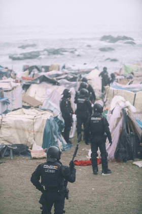 October 4, 2026, Ceuta, Ceuta, Spain: Riot police officers move into the shelters of the makeshift migrant camp on El Trampolin beach in Ceuta. Spanish National Police began evicting the makeshift camp on El Trampolin beach in Ceuta on October 4, where more than 3,000 migrants, most of them young Moroccan men, were living. Dozens of police vans, armoured vehicles of the Police Intervention Units (UIP), drones and boats took part in the operation. People were taken by bus to the temporary centre at the Tarajal border to be identified, and the authorities plan to clear the beach in phases before October 15. The camp grew after a mass arrival at the end of July 2026 set off a migration and political crisis. Ceuta Spain - ZUMAMigr 20261004_zip_s392_016 Copyright: xFabianxSuspensivox
