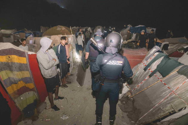 October 3, 2026, Ceuta, Ceuta, Spain: Riot police officers walk between the shelters of a makeshift migrant camp in Ceuta at night. Riot police escorted firefighters through the camp on the night of October 3 to put out the fires that people living there use to cook their food. Thousands of migrants, most of them young Moroccan men, have been living in makeshift settlements in the Spanish North African enclave of Ceuta since a mass arrival at the end of July 2026 set off a migration and political crisis. Ceuta Spain - ZUMArefi 20261003_zip_s392_008 Copyright: xFabianxSuspensivox