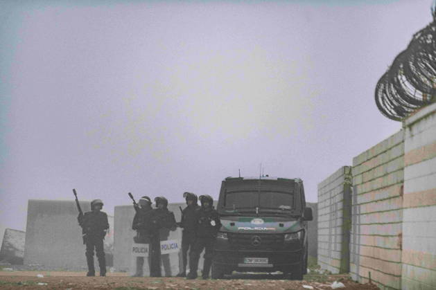 October 4, 2026, Ceuta, Ceuta, Spain: Riot police officers and a police van stand by a wall topped with razor wire in the fog during the eviction of the makeshift migrant camp on El Trampolin beach in Ceuta. Spanish National Police began evicting the makeshift camp on El Trampolin beach in Ceuta on October 4, where more than 3,000 migrants, most of them young Moroccan men, were living. Dozens of police vans, armoured vehicles of the Police Intervention Units (UIP), drones and boats took part in the operation. People were taken by bus to the temporary centre at the Tarajal border to be identified, and the authorities plan to clear the beach in phases before October 15. The camp grew after a mass arrival at the end of July 2026 set off a migr - ZUMAMigr 20261004_zip_s392_009 Copyright: xFabianxSuspensivox