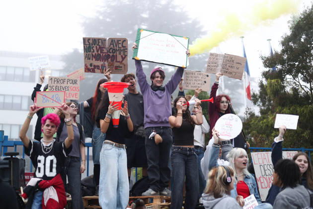 October 5, 2026, Bayonne, Nouvelle Aquitaine, France: High school students hold placards, one reading One teacher for 35 students, 5 riot police for 1 student , and a yellow smoke flare during a protest against the government outside the Reno Cassin high school in Bayonne, southwestern France, on October 5, 2026. Students have been blocking schools across France since September 21 to demand more teachers, smaller classes and better school buildings. Bayonne France - ZUMAb298 20261005_zsp_b298_007 Copyright: xJulesxBuonx