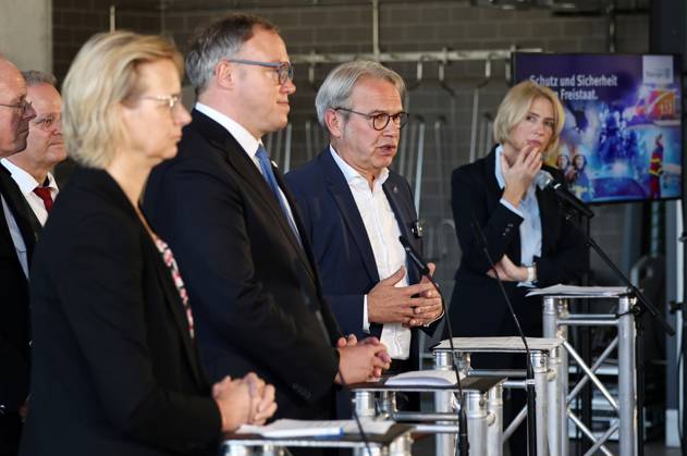 Regierungsmedienkonferenz 06.10.2026, Erfurt, Gefahrenabwehrzentrum Sued, Fahrzeughalle, die Landesregierung besser gegen hybride Bedrohungen, Cyberangriffe und Drohnen absichern, erstmals tritt das Thueringer Sicherheitskabinett zusammen, unter dem Leitgedanken Thueringen resilient machen beraten alle Mitglieder der Landesregierung gemeinsam mit Vertretern der Thueringer Sicherheitsbehoerden (Polizei, Landeskriminalamt, Verfassungsschutz, Landesverwaltungsamt und Landeskommando der Bundeswehr) über 11 Punkte fuer Schutz und Vorsorge Regierungsmedienkonferenz im Anschluss an das Sicherheitskabinett, bei der ueber die wichtigsten Ergebnisse informiert wird im Bild: Finanzministerin Katja Wolf (Thueringen.Gerecht), Ministerpraesident Mario V