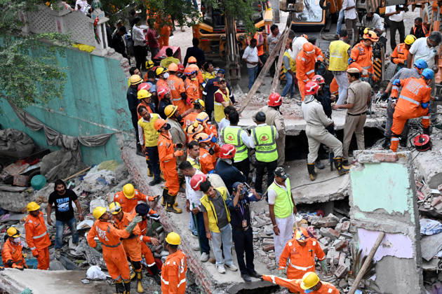 NEW DELHI, INDIA - OCTOBER 7: National Disaster Response Force (NDRF) jawans, Delhi Fire Service personnel, and local residents navigate heavy rubble during a search and rescue operation after a four-storey residential building collapsed in the New Seemapuri area of Shahdara on October 7, 2026, in New Delhi, India. The structural collapse occurred around 3:30 PM behind the local fish market, trapping multiple residents under concrete slabs and damaging two adjoining houses. At least one minor died while eight people were rescued and rushed to Rajiv Gandhi Super Speciality Hospital for emergency medical treatment as sniffer dogs and excavators worked late into the evening to locate remaining trapped survivors. (Photo by Ishant Chauhan Hindus
