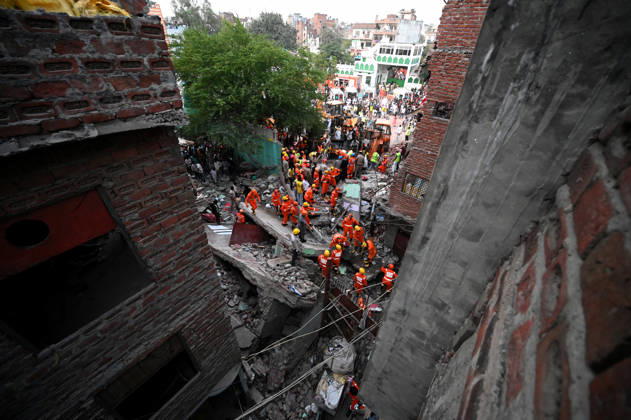 NEW DELHI, INDIA - OCTOBER 7: National Disaster Response Force (NDRF) jawans, Delhi Fire Service personnel, and local residents navigate heavy rubble during a search and rescue operation after a four-storey residential building collapsed in the New Seemapuri area of Shahdara on October 7, 2026, in New Delhi, India. The structural collapse occurred around 3:30 PM behind the local fish market, trapping multiple residents under concrete slabs and damaging two adjoining houses. At least one minor died while eight people were rescued and rushed to Rajiv Gandhi Super Speciality Hospital for emergency medical treatment as sniffer dogs and excavators worked late into the evening to locate remaining trapped survivors. (Photo by Ishant Chauhan Hindus