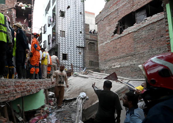 NEW DELHI, INDIA - OCTOBER 7: National Disaster Response Force (NDRF) jawans, Delhi Fire Service personnel, and local residents navigate heavy rubble during a search and rescue operation after a four-storey residential building collapsed in the New Seemapuri area of Shahdara on October 7, 2026, in New Delhi, India. The structural collapse occurred around 3:30 PM behind the local fish market, trapping multiple residents under concrete slabs and damaging two adjoining houses. At least one minor died while eight people were rescued and rushed to Rajiv Gandhi Super Speciality Hospital for emergency medical treatment as sniffer dogs and excavators worked late into the evening to locate remaining trapped survivors. (Photo by Ishant Chauhan Hindus