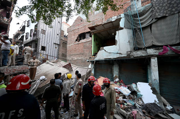NEW DELHI, INDIA - OCTOBER 7: National Disaster Response Force (NDRF) jawans, Delhi Fire Service personnel, and local residents navigate heavy rubble during a search and rescue operation after a four-storey residential building collapsed in the New Seemapuri area of Shahdara on October 7, 2026, in New Delhi, India. The structural collapse occurred around 3:30 PM behind the local fish market, trapping multiple residents under concrete slabs and damaging two adjoining houses. At least one minor died while eight people were rescued and rushed to Rajiv Gandhi Super Speciality Hospital for emergency medical treatment as sniffer dogs and excavators worked late into the evening to locate remaining trapped survivors. (Photo by Ishant Chauhan Hindus