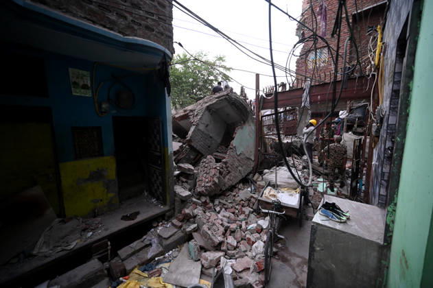 NEW DELHI, INDIA - OCTOBER 7: National Disaster Response Force (NDRF) jawans, Delhi Fire Service personnel, and local residents navigate heavy rubble during a search and rescue operation after a four-storey residential building collapsed in the New Seemapuri area of Shahdara on October 7, 2026, in New Delhi, India. The structural collapse occurred around 3:30 PM behind the local fish market, trapping multiple residents under concrete slabs and damaging two adjoining houses. At least one minor died while eight people were rescued and rushed to Rajiv Gandhi Super Speciality Hospital for emergency medical treatment as sniffer dogs and excavators worked late into the evening to locate remaining trapped survivors. (Photo by Ishant Chauhan Hindus