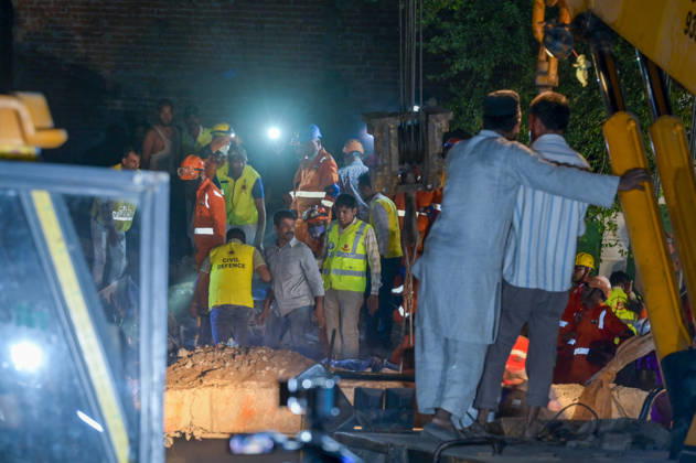 NEW DELHI, INDIA - OCTOBER 7: National Disaster Response Force (NDRF) jawans, Delhi Fire Service personnel, and local residents navigate heavy rubble during a search and rescue operation after a four-storey residential building collapsed in the New Seemapuri area of Shahdara on October 7, 2026, in New Delhi, India. The structural collapse occurred around 3:30 PM behind the local fish market, trapping multiple residents under concrete slabs and damaging two adjoining houses. At least one minor died while eight people were rescued and rushed to Rajiv Gandhi Super Speciality Hospital for emergency medical treatment as sniffer dogs and excavators worked late into the evening to locate remaining trapped survivors. (Photo by Raj K Raj Hindustan T