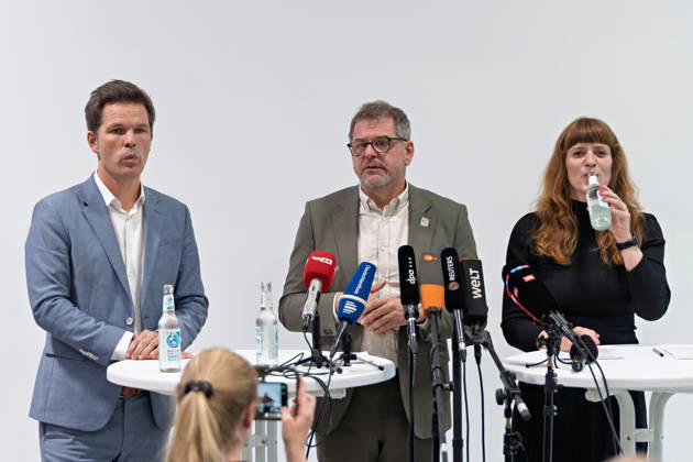 Berlin, October 8, 2026: Werner Graf of Alliance 90 The Greens (center) speaks alongside Steffen Krach of the SPD (left) during a joint press statement following the conclusion of their parties’ preliminary talks in the foyer of the Haus der Statistik, Kerstin Wolter Ehling of The Left (right) drinks from a water bottle. Joint press statement by The Left, the Greens, and the SPD in Berlin