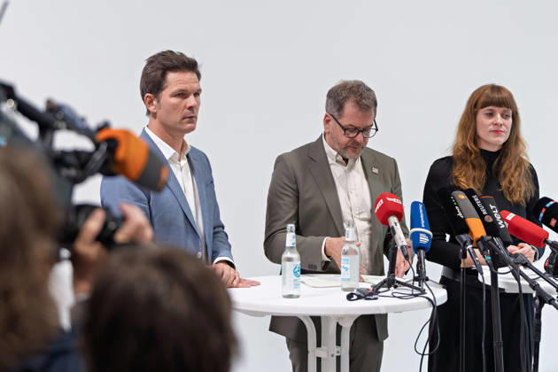 Berlin, October 8, 2026 Werner Graf, Alliance 90 The Greens, M looks down at his notes alongside Steffen Krach (SPD, l) and Kerstin Wolter Ehling (Die Linke, r) during a joint press statement following the conclusion of their parties’ preliminary talks in the foyer of the Haus der Statistik; a camera crew is visible in the foreground. Press statement by Die Linke, the Greens, and the