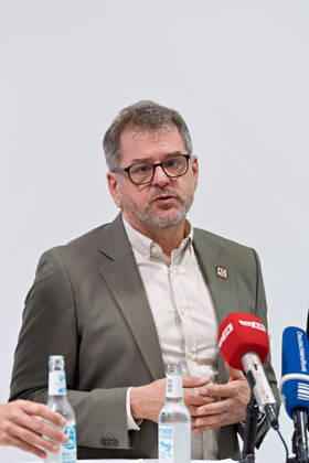 Berlin, October 8, 2026—Werner Graf of Alliance 90 The Greens speaks during a joint press statement by The Left Berlin, Alliance 90 The Greens Berlin, and the SPD Berlin following the conclusion of preliminary talks in the foyer of the Haus der Statistik, speaking into the media microphones Press statement by Die Linke, the Greens, and the SPD in Berlin