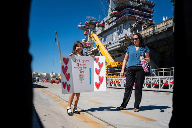 October 8, 2026, Coronado, California, United States: A young girl holds a handmade sign reading Ã¢â‚¬oeI ve grown 3 inches waiting for youÃ¢â‚¬Â alongside a family member as they await the return of the aircraft carrier USS Abraham Lincoln (CVN 72) at Naval Air Station North Island in Coronado, California, on October 8, 2026, following a deployment. Coronado United States - ZUMAg374 20261008_znp_g374_025 Copyright: xLoganxGrahamx