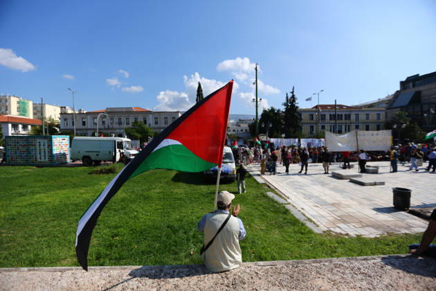 October 10, 2026, Athens, Attica, GREECE: A demonstrator holding a Palestinian flag sits on a low wall as protesters gather nearby. Athens GREECE - ZUMAx103 20261010_zip_x103_008 Copyright: xHarrisxXanthopoulosx