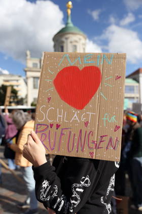 A protester stands in the Alter Markt holding a sign that reads My Heart Beats for Exams during a demonstration calling for the Federal Constitutional Court to review far-right parties, Potsdam, October 10, 2026. Protest demonstration in Potsdam