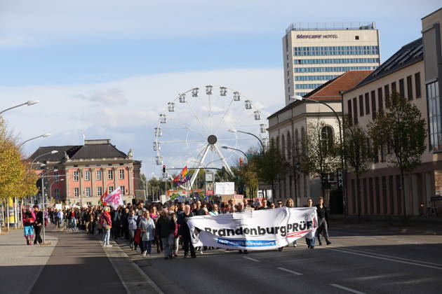 Protesters walk down Breite Straße carrying a banner reading Brandenburg: Investigate during a demonstration calling for the Federal Constitutional Court to review far-right parties, Potsdam, October 10, 2026. Investigate demonstration in Potsdam