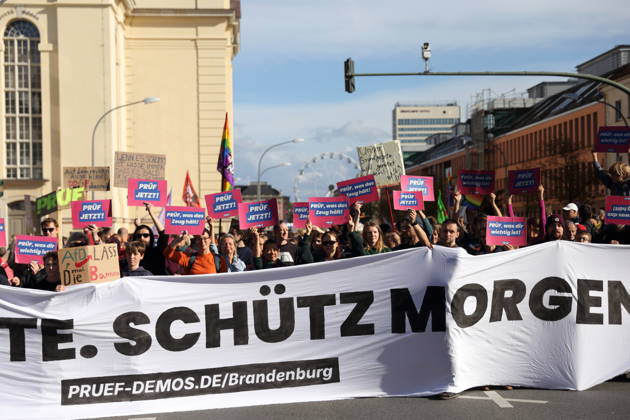 Protesters stand on Breite Straße holding a banner reading Review Today, Ban Tomorrow during a demonstration calling for the Federal Constitutional Court to review far-right parties, Potsdam, October 10, 2026. Review Demonstration in Potsdam