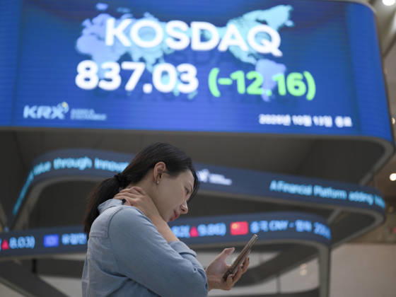 South Korea Stocks Plunge As KOSPI Drops Sharply At KRX In Seoul A Korea Exchange (KRX) employee looks at her smartphone in front of a board displaying the closing KOSDAQ index at 837.03 (-12.16) in Yeouido, Seoul, South Korea, on October 13, 2026. Seoul Seoul South Korea  Copyright: xChrisxJungx originalFilename: jung-southkor261013_npg06.jpg