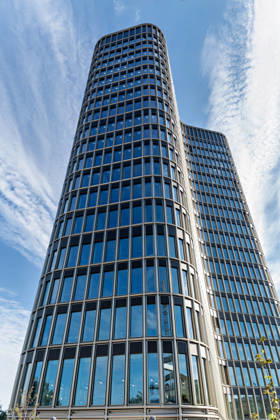 Berlin, 13.10.2026: Der Turm des neuen DKB-Campus in der Europacity in Berlin-Mitte aus der Froschperspektive, darüber Schleierwolken am blauen Himmel. Die Deutsche Kreditbank AG (DKB) hat ihren neuen Hauptsitz heute offiziell eröffnet. Der von Kleihues + Kleihues entworfene, rund 82 Meter hohe Komplex besteht aus drei Gebäudeteilen mit fünf, elf und 19 Geschossen und rund 35.000 Quadratmetern Mietfläche; entwickelt wurde er von der CA Immo unter dem Projektnamen Upbeat. Rund 2.600 Mitarbeitende des DKB-Konzerns, die bislang auf mehrere Berliner Standorte verteilt waren, arbeiten nun gemeinsam im Campus. Die DKB ist Exklusivmieterin und hat einen Mietvertrag über 15 Jahre abgeschlossen. DKB eröffnet neuen Hauptsitz in der Berli