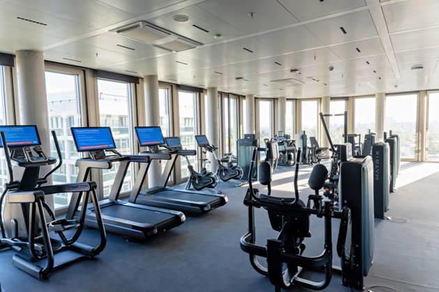 Berlin, 13.10.2026: Fitnessbereich mit Laufbändern, Crosstrainern und Ergometern im neuen DKB-Campus in der Europacity in Berlin-Mitte; die Fitnessfläche gehört zu den Gesundheitsangeboten für die Mitarbeitenden. Die Deutsche Kreditbank AG (DKB) hat ihren neuen Hauptsitz heute offiziell eröffnet. Der von Kleihues + Kleihues entworfene, rund 82 Meter hohe Komplex besteht aus drei Gebäudeteilen mit fünf, elf und 19 Geschossen und rund 35.000 Quadratmetern Mietfläche; entwickelt wurde er von der CA Immo unter dem Projektnamen Upbeat. Rund 2.600 Mitarbeitende des DKB-Konzerns, die bislang auf mehrere Berliner Standorte verteilt waren, arbeiten nun gemeinsam im Campus. Die DKB ist Exklusivmieterin und hat einen Mietvertrag über 15