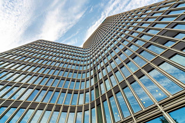 Berlin, 13.10.2026: Die geschwungene Glasfassade des neuen DKB-Campus in der Europacity in Berlin-Mitte aus der Froschperspektive vor Schleierwolken am blauen Himmel. Die Deutsche Kreditbank AG (DKB) hat ihren neuen Hauptsitz heute offiziell eröffnet. Der von Kleihues + Kleihues entworfene, rund 82 Meter hohe Komplex besteht aus drei Gebäudeteilen mit fünf, elf und 19 Geschossen und rund 35.000 Quadratmetern Mietfläche; entwickelt wurde er von der CA Immo unter dem Projektnamen Upbeat. Rund 2.600 Mitarbeitende des DKB-Konzerns, die bislang auf mehrere Berliner Standorte verteilt waren, arbeiten nun gemeinsam im Campus. Die DKB ist Exklusivmieterin und hat einen Mietvertrag über 15 Jahre abgeschlossen. DKB eröffnet neuen Hauptsit