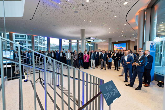 Berlin, 13.10.2026: Zahlreiche Gäste verfolgen die Eröffnungsfeier im Foyer des neuen DKB-Campus in der Europacity in Berlin-Mitte. Die Deutsche Kreditbank AG (DKB) hat ihren neuen Hauptsitz heute offiziell eröffnet. Der von Kleihues + Kleihues entworfene, rund 82 Meter hohe Komplex besteht aus drei Gebäudeteilen mit fünf, elf und 19 Geschossen und rund 35.000 Quadratmetern Mietfläche; entwickelt wurde er von der CA Immo unter dem Projektnamen Upbeat. Rund 2.600 Mitarbeitende des DKB-Konzerns, die bislang auf mehrere Berliner Standorte verteilt waren, arbeiten nun gemeinsam im Campus. Die DKB ist Exklusivmieterin und hat einen Mietvertrag über 15 Jahre abgeschlossen. Die DKB unterstreicht mit dem langfristig angelegten Standort