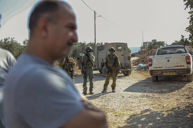 Settlers Disrupt Turmus Ayya Harvest A man stands in the foreground of a dirt road as armed Israeli soldiers stand near an armored vehicle and a white pickup truck in Turmus Ayya, near Ramallah, in the Israeli-occupied West Bank, on October 13, 2026. Palestinian news agency WAFA, citing local sources, reported that Israeli settlers attacked the town and tried to prevent residents from reaching their land to harvest olives. Ramallah West Bank Palestinian Territories Copyright: xMohammadxNazalx