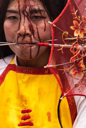 October 15, 2026, Trang, Thailand: A devotee with a skewer piercing her cheek participates in a street procession during the Vegetarian Festival..The annual Vegetarian Festival is held in Bangkok and many parts of southern Thailand, including Trang, Phang Nga, and Phuket, where worshippers refrain from eating animal products over the nine days, coinciding with the celebration of the Nine Emperor Gods. Trang Thailand - ZUMAs197 20261015_aaa_s197_014 Copyright: xPeeraponxBoonyakiatx