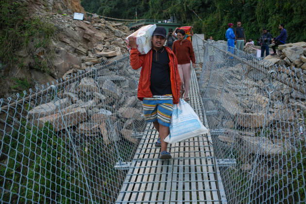 KATHMANDU, NEPAL - OCTOBER 15: Local residents carry supplies while preparing to cross the newly installed Bailey bridge connecting the border areas of Nuwakot and Rasuwa districts on October 15, 2026 in Nuwakot, Nepal. The bridge was installed to restore road connectivity after severe flooding destroyed existing bridges on August 26, 2026.  Copyright: xChinaxNewsxServicex 111674496628