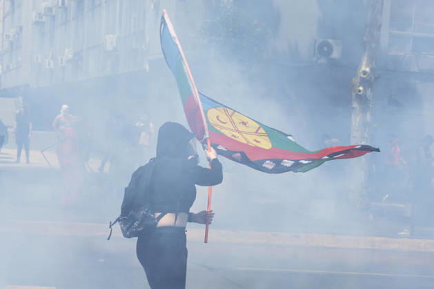 October 19, 2026, Santiago, Chile: A demonstrator in the smoke flies a flag that symbolizes the Mapuche people. In the center of the capital of Chile, different incidents took place between demonstrators and the police. The riots were carried out during the commemoration of the 7 years after the social outcast that happened on October 18, 2019. Santiago Chile - ZUMAs197 20261019_aaa_s197_004 Copyright: xSebastianxNancox