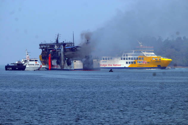 Efforts are underway to extinguish a fire that broke out on a passenger ferry in Indonesia s Cilegon PELABUHAN MERAK, CILEGON, INDONESIA - OCTOBER 21: Fireboats take turns spraying water onto the passenger ferry KMP Batumandi to cool down the vessel after it caught fire while preparing to dock off Merak Port in Cilegon, Banten, Indonesia on Wednesday, October 21, 2026. The vessel caught fire on Tuesday, October 20, and rescue operations remain underway as the ship continues to emit smoke. Water is continuously sprayed to cool the vehicle deck containing numerous cars, motorcycles, buses, and trucks, while authorities confirm no fatalities have been reported. Dasril Roszandi Anadolu Pelabuhan Merak Indonesia. Editorial use only. Please get Copyright: x2026xAnadoluxDasrilxRoszandix