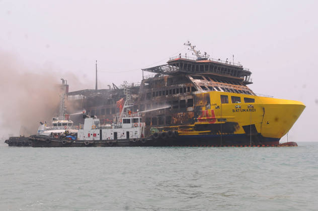 Efforts are underway to extinguish a fire that broke out on a passenger ferry in Indonesia s Cilegon PELABUHAN MERAK, CILEGON, INDONESIA - OCTOBER 21: Fireboats take turns spraying water onto the passenger ferry KMP Batumandi to cool down the vessel after it caught fire while preparing to dock off Merak Port in Cilegon, Banten, Indonesia on Wednesday, October 21, 2026. The vessel caught fire on Tuesday, October 20, and rescue operations remain underway as the ship continues to emit smoke. Water is continuously sprayed to cool the vehicle deck containing numerous cars, motorcycles, buses, and trucks, while authorities confirm no fatalities have been reported. Dasril Roszandi Anadolu Pelabuhan Merak Indonesia. Editorial use only. Please get Copyright: x2026xAnadoluxDasrilxRoszandix