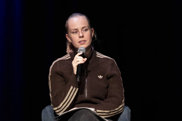 Poetry artist and author Clara LOESEL LÖSEL, focused and pensive, during her reading—a preview of her new book, *Ich dachte, sowas fühle nur ich*—seated with a microphone; single frame, single photo, at the Theater am Tanzbrunnen, Cologne, on October 23, 2026