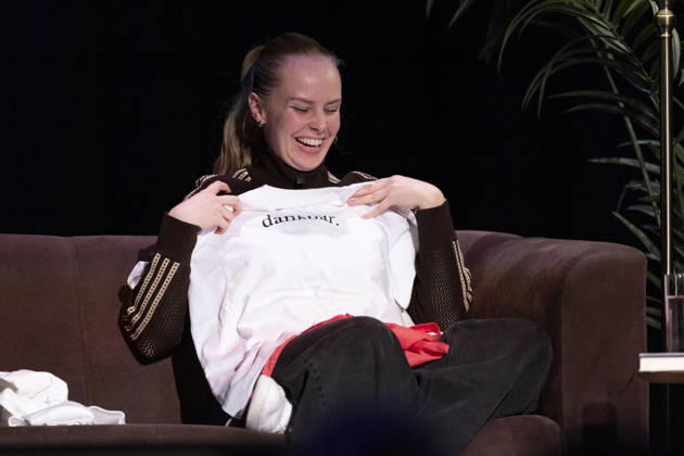 Poetry artist and author Clara LOESEL LÖSEL, wearing a T-shirt with the word grateful printed on it, during her reading—a preview event for her new book *Ich dachte, sowas fühle nur ich*—sitting on a sofa; single frame, single photo, at the Theater am Tanzbrunnen, Cologne, on October 23, 2026