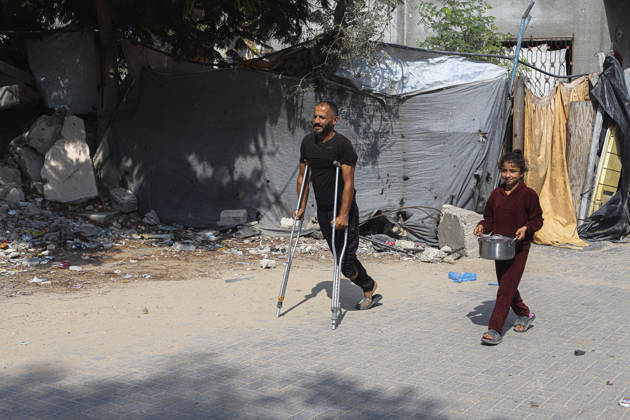 Gaza Palestinians Food Shortages 2026 A Palestinian man using crutches walks with a young girl carrying a metal cooking pot along a damaged street in Jabalia Refugee Camp, northern Gaza Strip, Palestine, on October 24, 2026. The UN says widespread damage, displacement and food shortages have left families across Gaza heavily dependent on humanitarian assistance, with food distributions reduced in October amid funding constraints. Jabalia Gaza Strip Palestinian Territories Copyright: xRamezxHabboubx