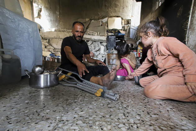Gaza Palestinians Food Shortages 2026 A Palestinian man using crutches sits with children as they eat a meal received from a charity kitchen inside a damaged building in Jabalia Refugee Camp, northern Gaza Strip, Palestine, on October 24, 2026. The UN says widespread damage, displacement and food shortages have left families across Gaza heavily dependent on humanitarian assistance, with food distributions reduced in October amid funding constraints. Jabalia Gaza Strip Palestinian Territories Copyright: xRamezxHabboubx